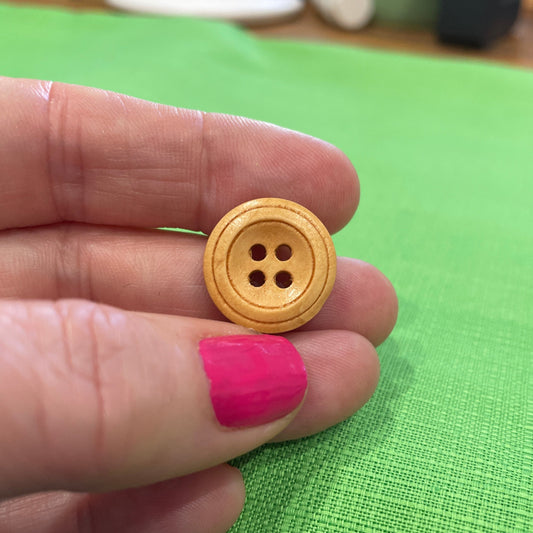 Gold button held between fingers against a green background
