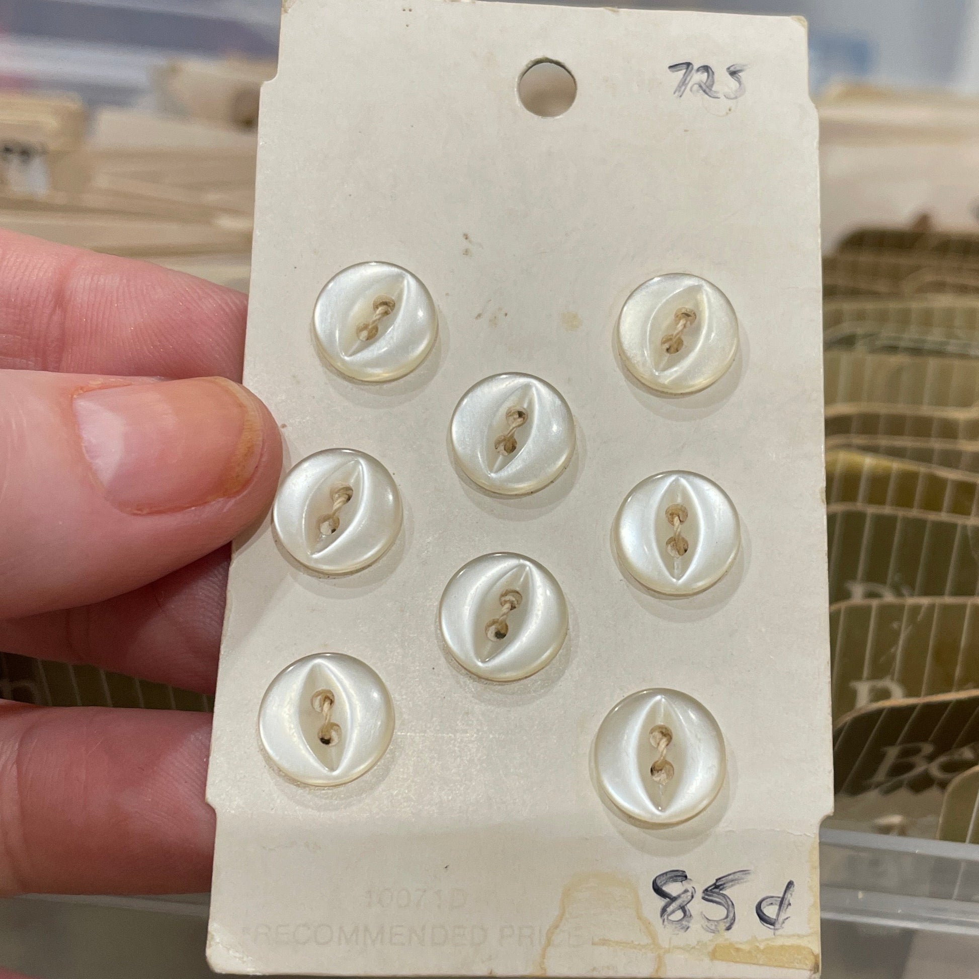 Card with buttons held by a hand against a blurred background of storage containers.