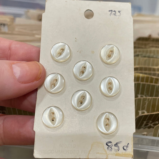 Card with buttons held by a hand against a blurred background of storage containers.