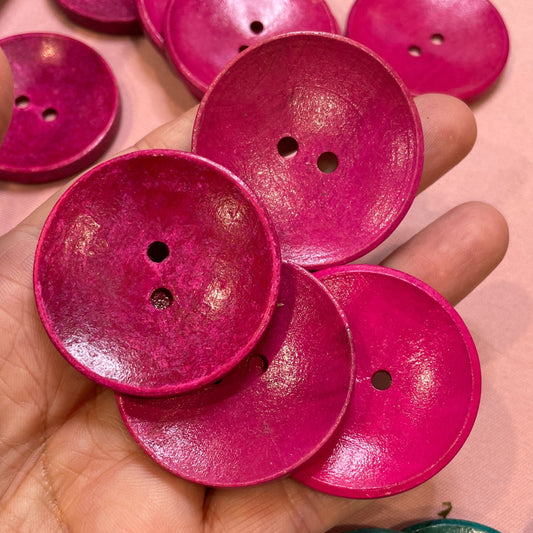 Hand holding pink buttons with a pink background