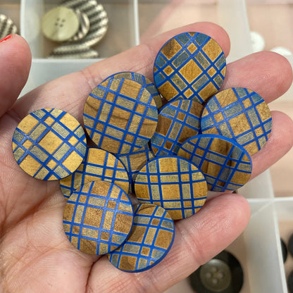 Hand holding blue and gold checkered buttons with a button organizer in the background