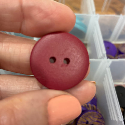 Hand holding a red button with a background of a storage box with various items.