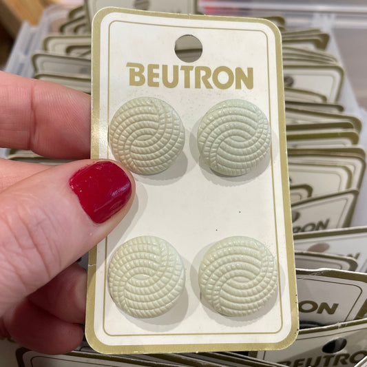 Hand holding a package of Beutron buttons with a blurred background