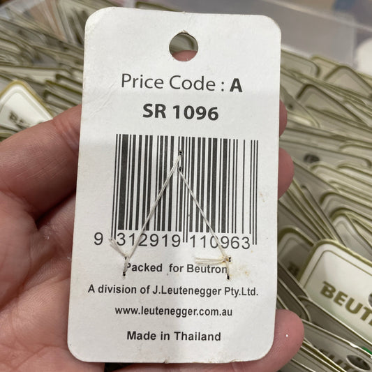 Hand holding a product tag with a barcode and text, blurred background