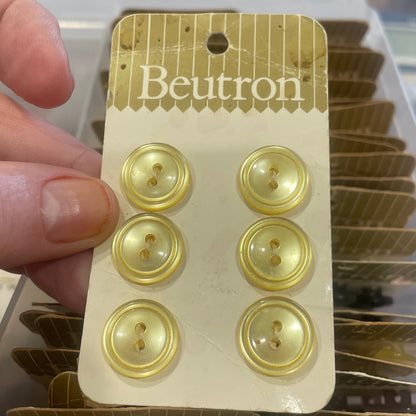 Packaging of gold buttons with 'Beutron' branding held by a hand.