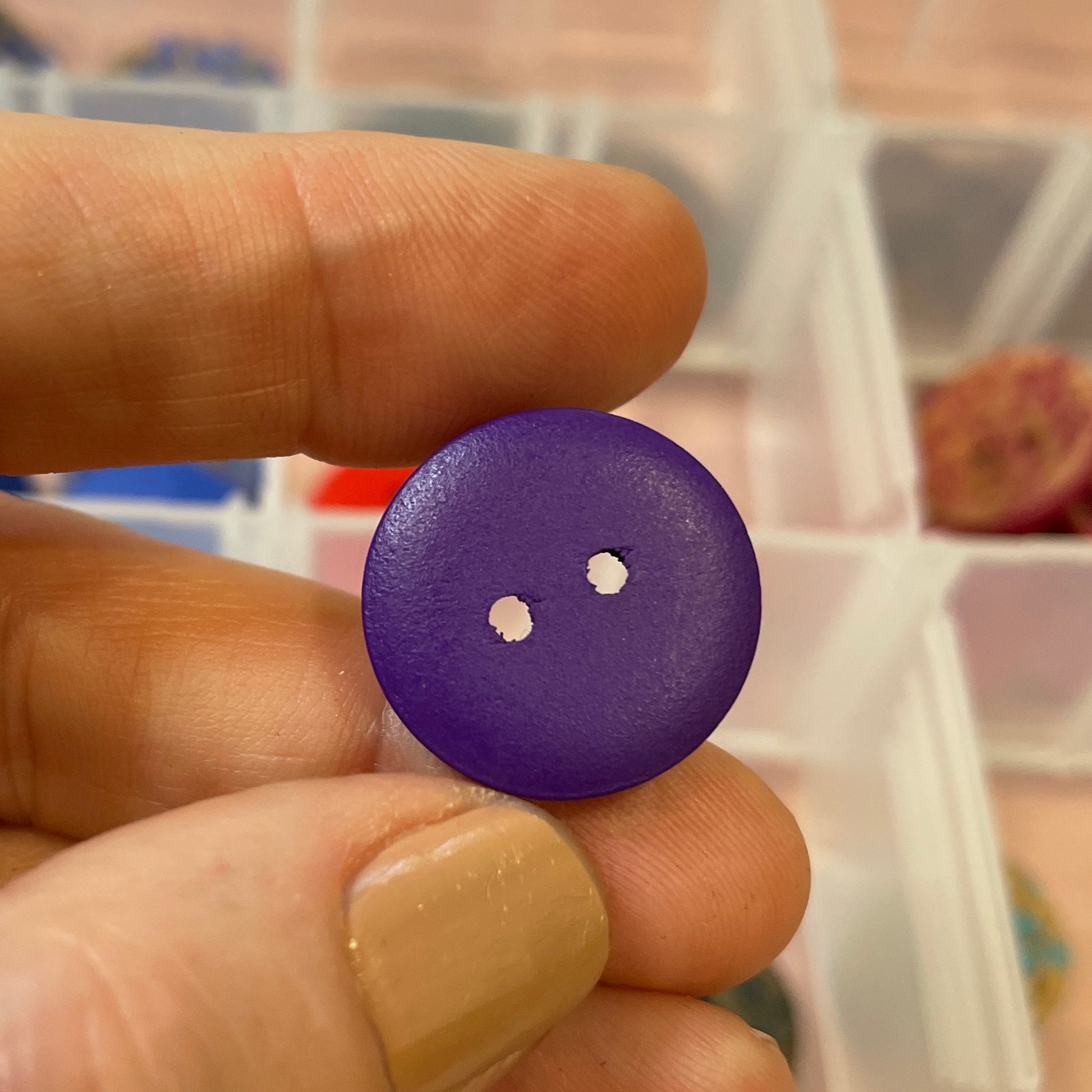 Purple button held between fingers with a blurred background
