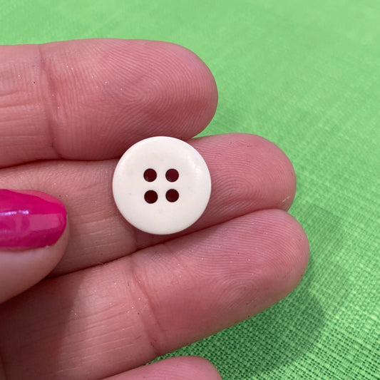 White button held between fingers against a green background