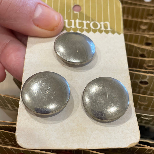 Hand holding a card with three metal buttons.