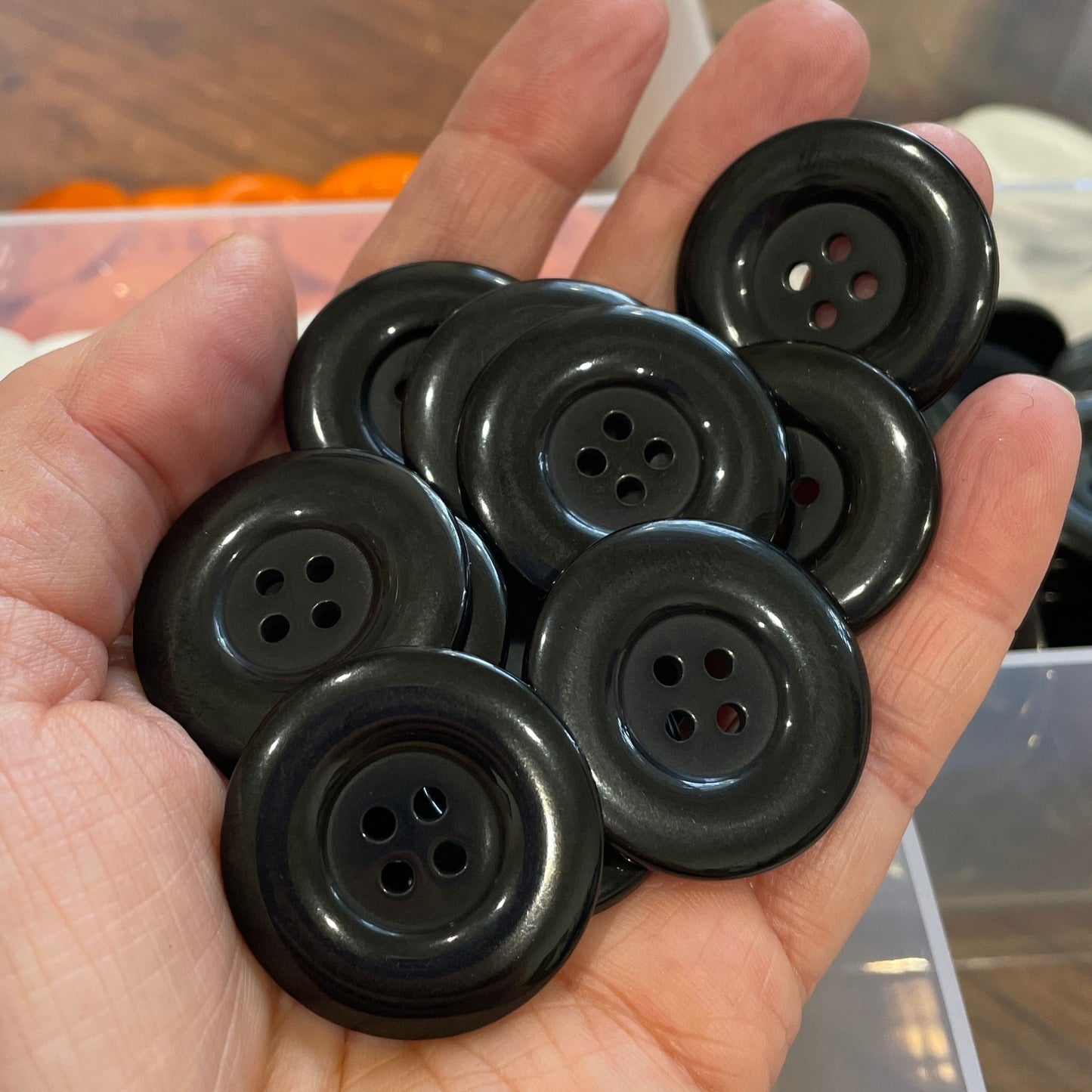 Hand holding black buttons with a blurred background