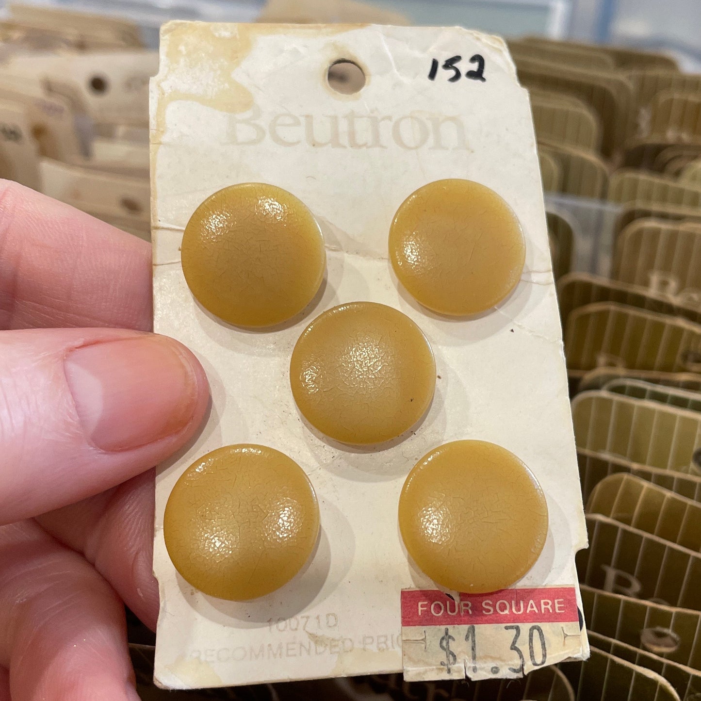 Hand holding a package of beige buttons with a blurred background