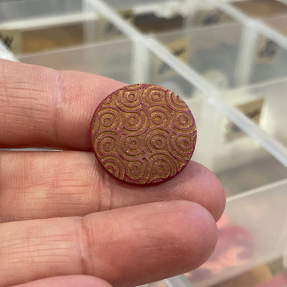 Wooden button held between fingers with a clear plastic organizer in the background