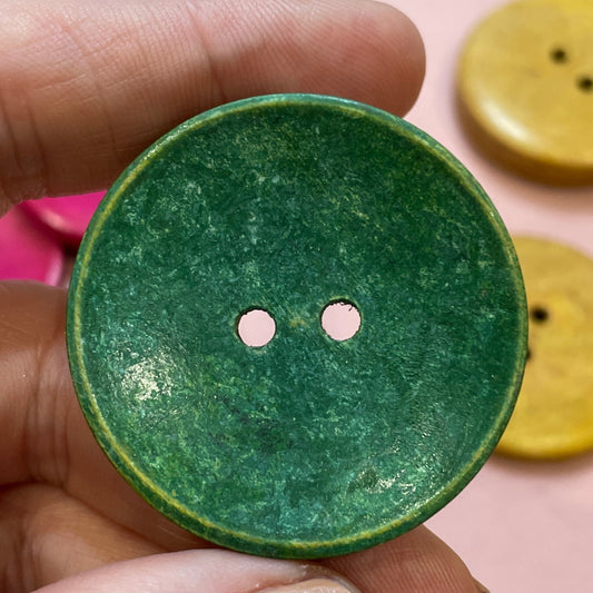 Hand holding a green button with other colorful buttons in the background