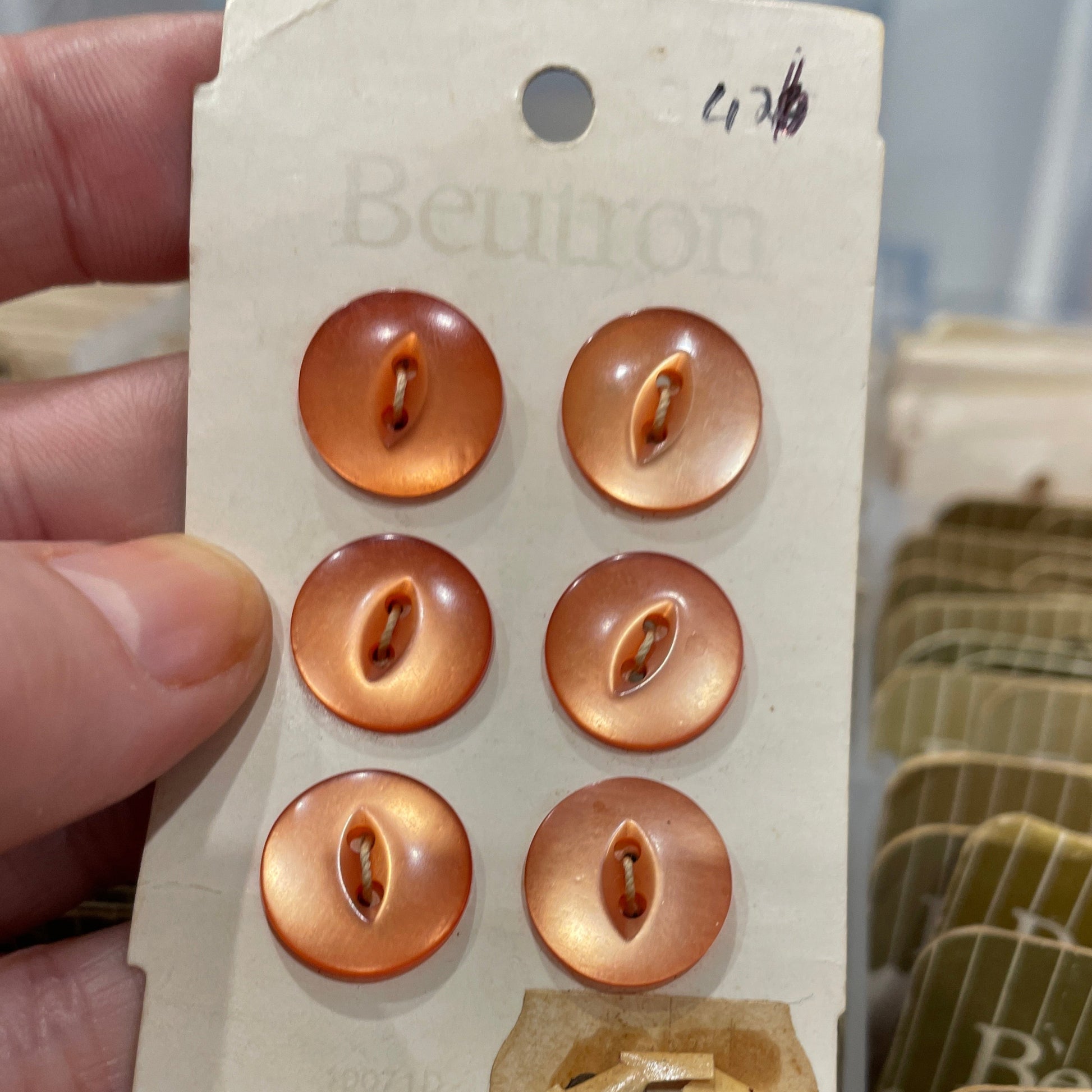 Set of gold buttons on a Beloved brand card held by a hand.
