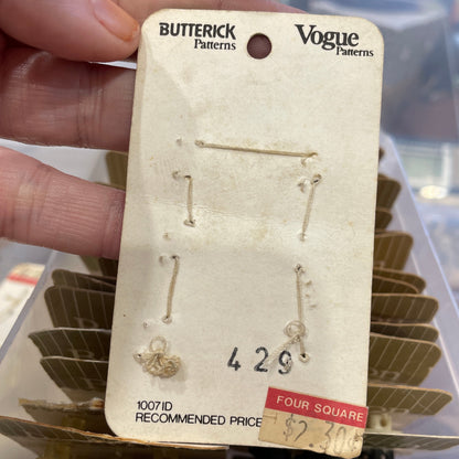 Card held by a hand, with a blurred background of more earrings.