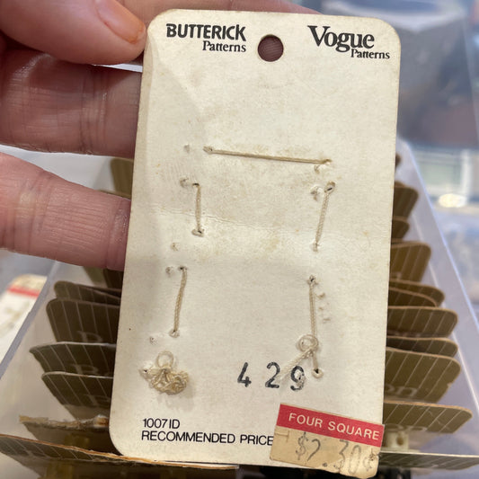 Card held by a hand, with a blurred background of more earrings.