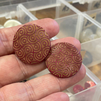 Hand holding two wooden buttons with a clear container of buttons in the background