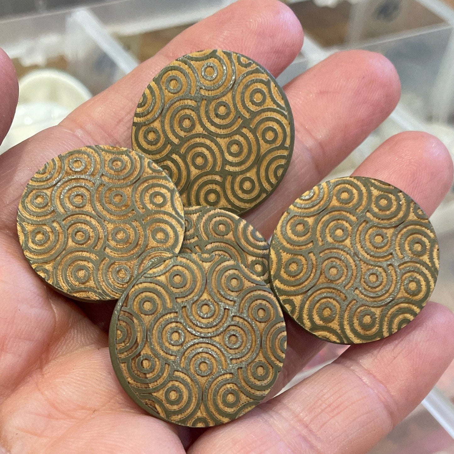 Hand holding buttons with a clear plastic container in the background