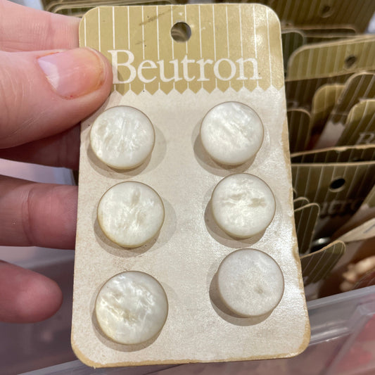 Hand holding a button card, against a blurred background.