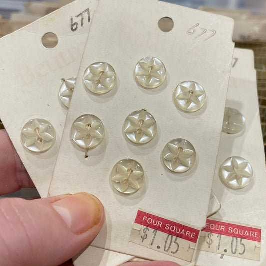 Hand holding a sheet of decorative buttons with a blurred background