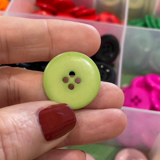 Hand holding a green button with a colorful array of buttons in the background