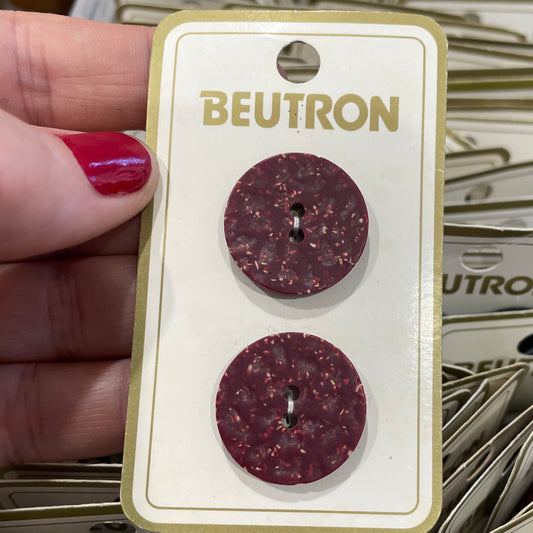 Buttons on a BEUTRON card held in front of more earrings on cards.