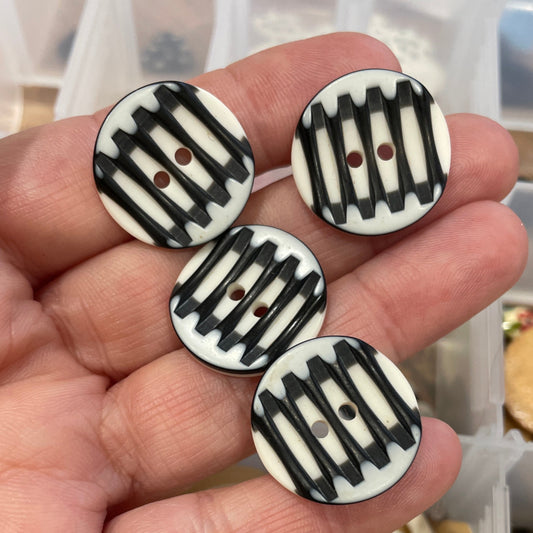 Hand holding decorative buttons with a container of buttons in the background