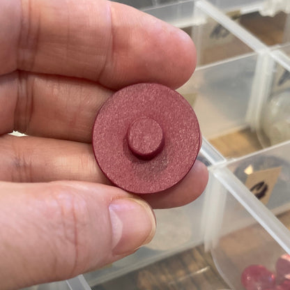 Hand holding a button with a clear container of buttons in the background