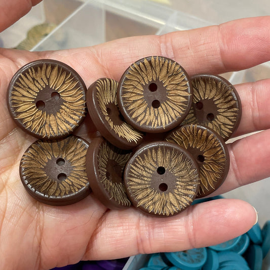 Hand holding brown buttons with a container of blue buttons in the background