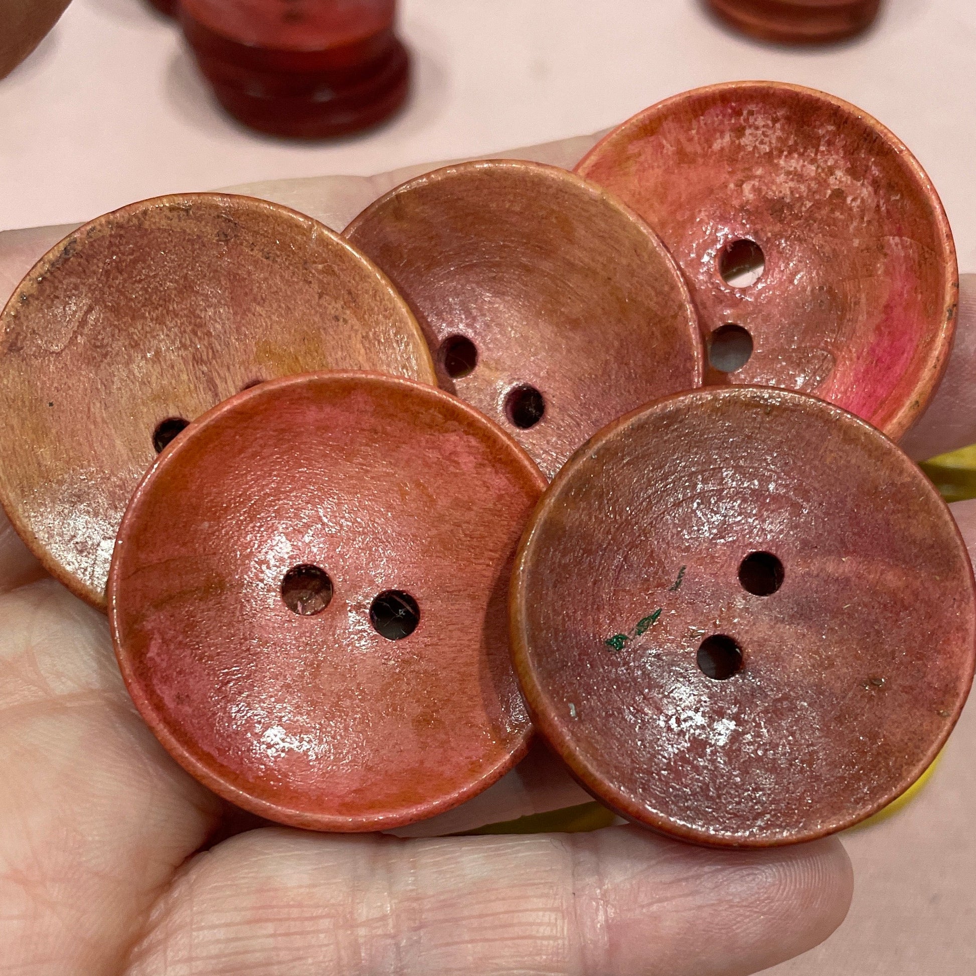 Hand holding a cluster of brown buttons with a light background