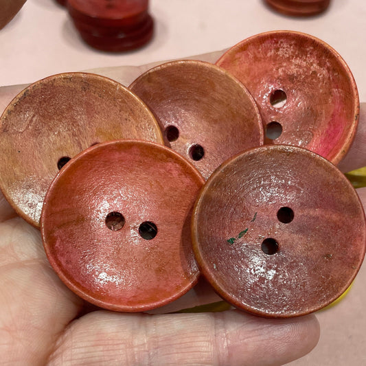 Hand holding a cluster of brown buttons with a light background