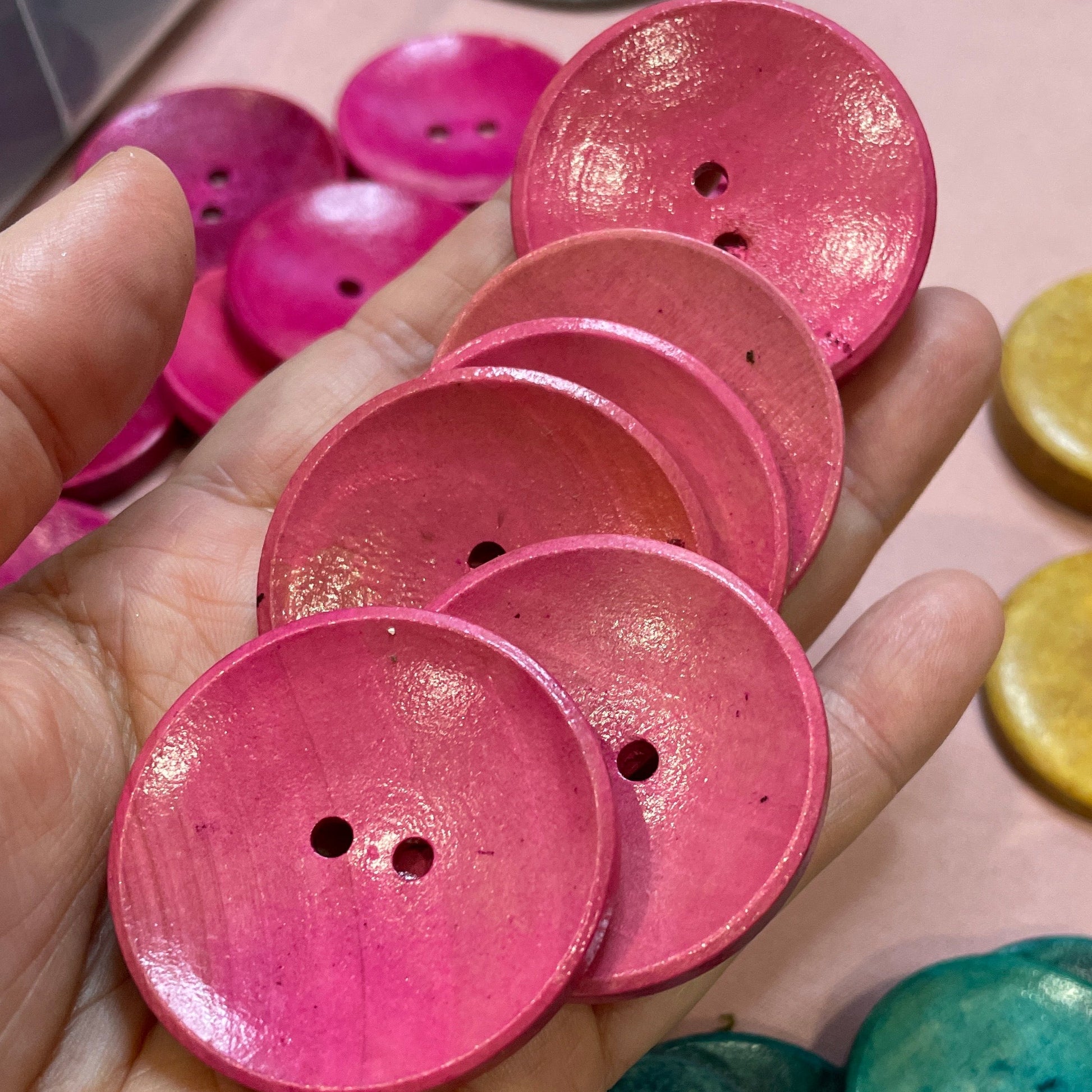 Hand holding pink buttons with colorful buttons in the background
