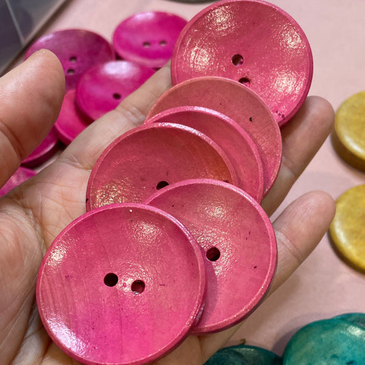 Hand holding pink buttons with colorful buttons in the background
