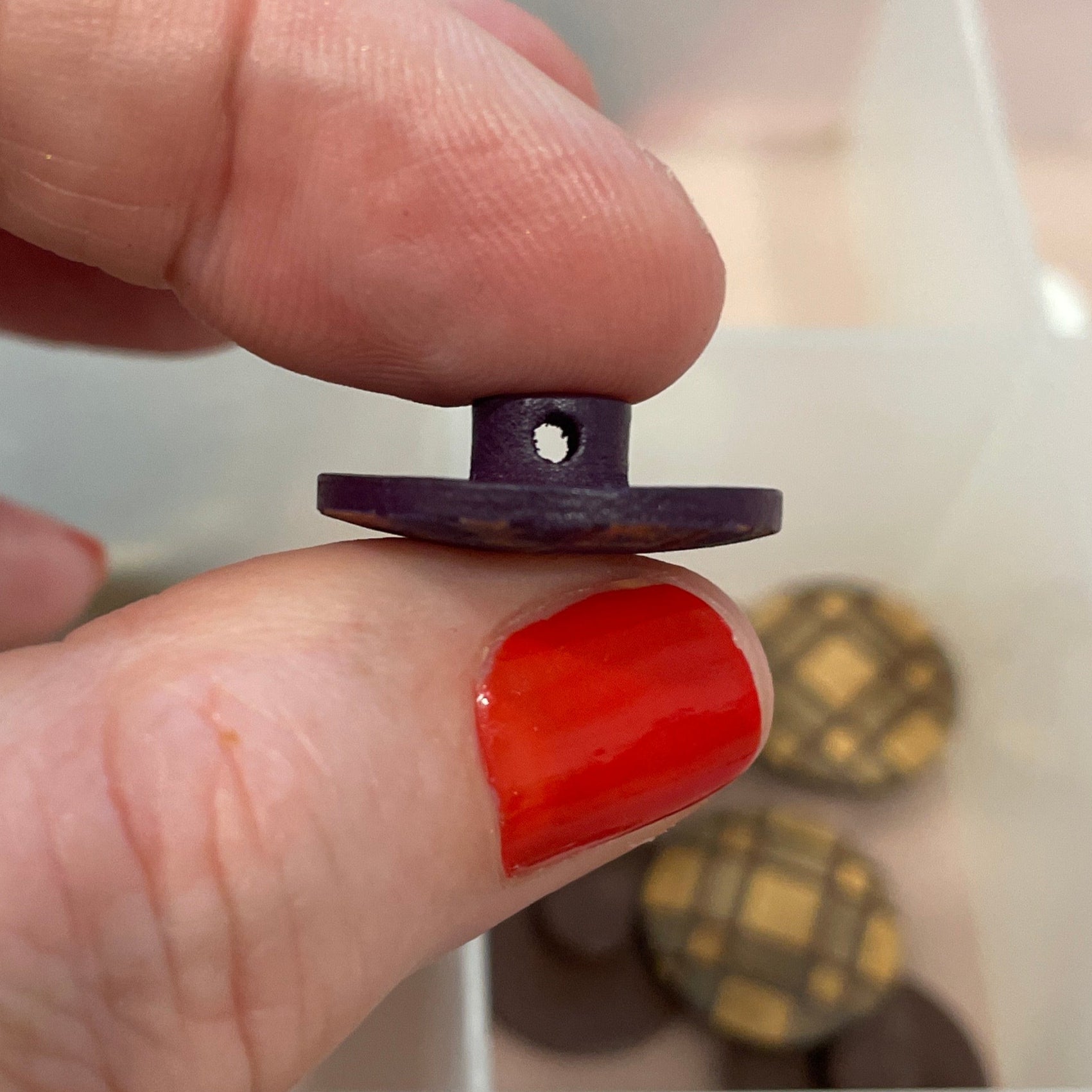 Person holding a small purple button with a collection of buttons in the background