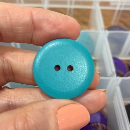 Hand holding a blue button with a blurred background of a storage box with various items.