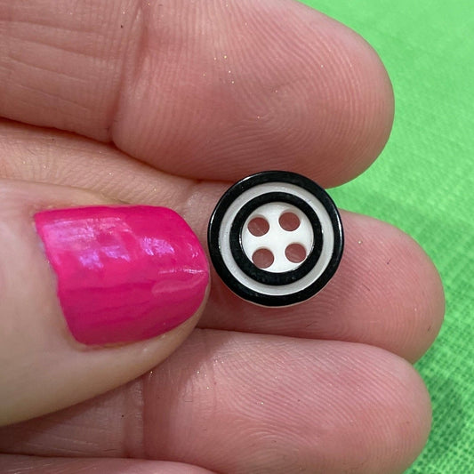 Small pink object with a black and white design held between fingers against a green background