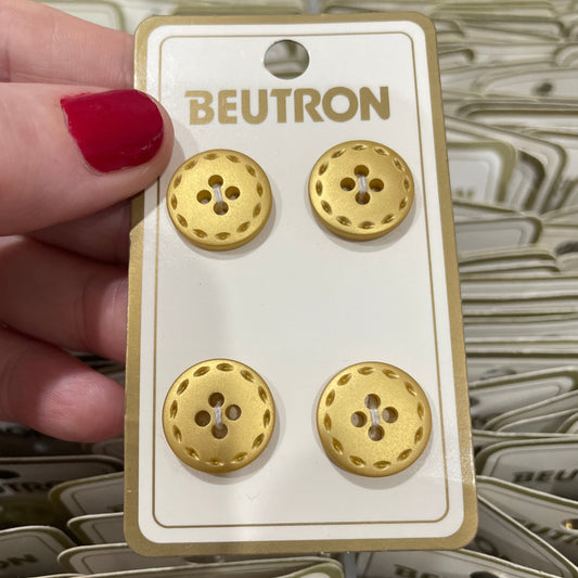 Gold buttons on a BEUTRON branded card held by a hand with red nail polish.