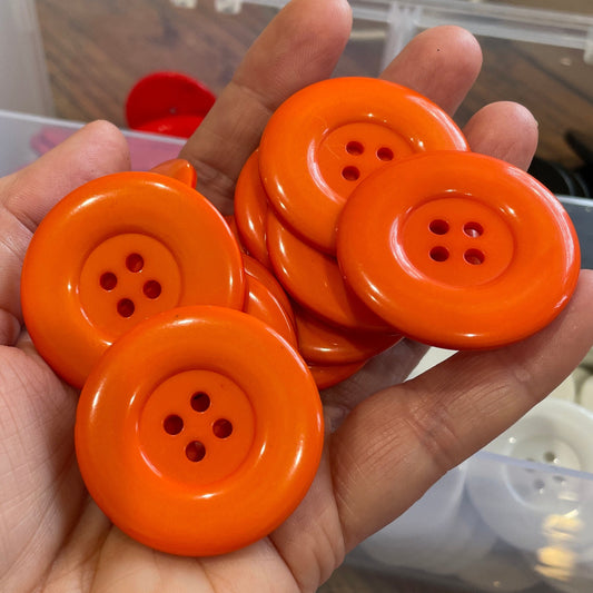 Hand holding orange buttons with a blurred background of more buttons.