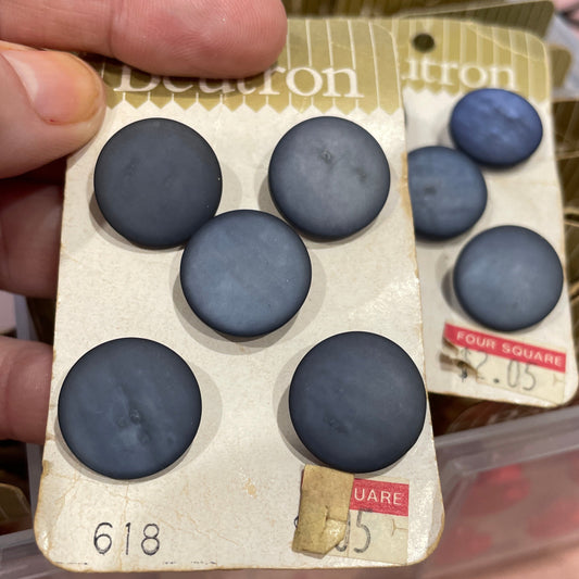 Pack of six blue buttons held by a hand with a blurred background