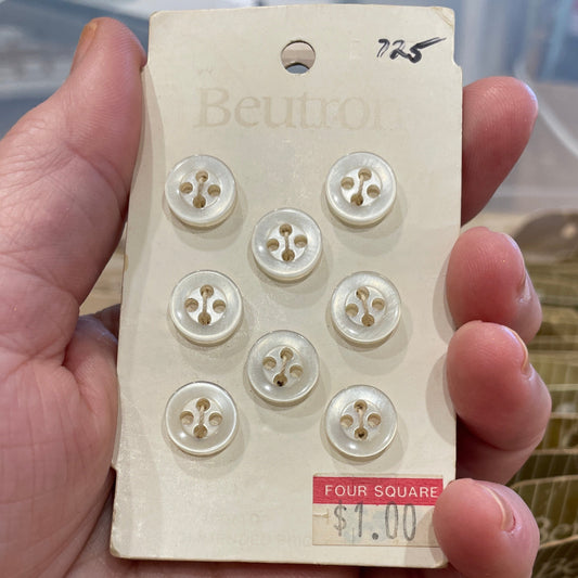 Hand holding a block of buttons with a brand label, blurred background