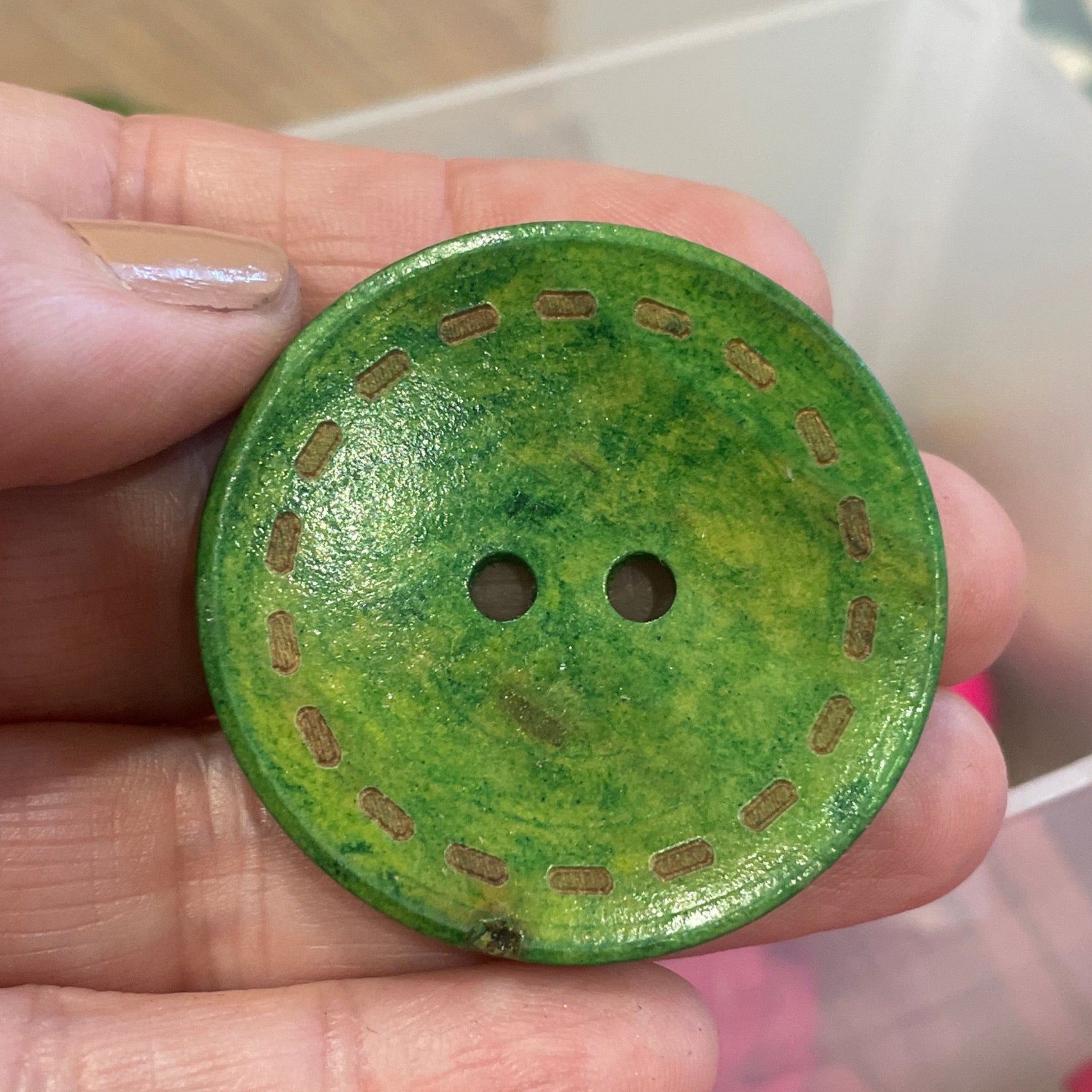 Green button held in a hand with pink buttons in the background