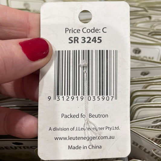Close-up of a product tag with a barcode and text, held by a hand with red nail polish.