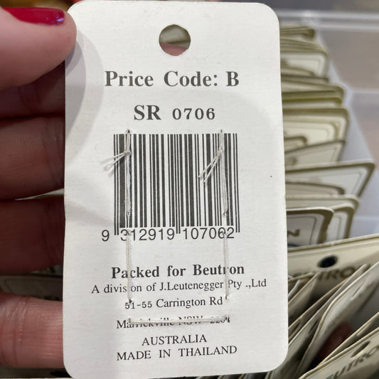 Close-up of a product tag with a barcode and text, held by a hand.