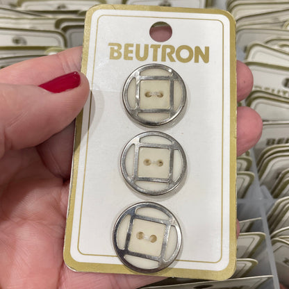 Hand holding a package of Beutron buttons with a clear background