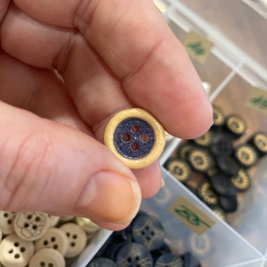 Hand holding a button with a blurred background of button assortment