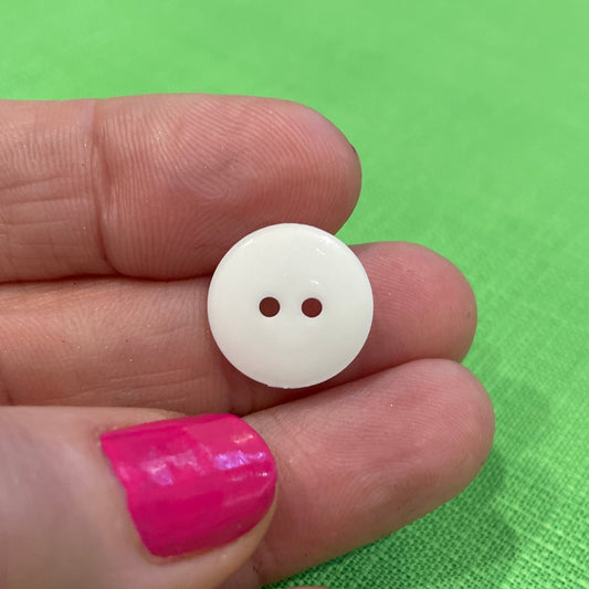 White button held between fingers against a green background