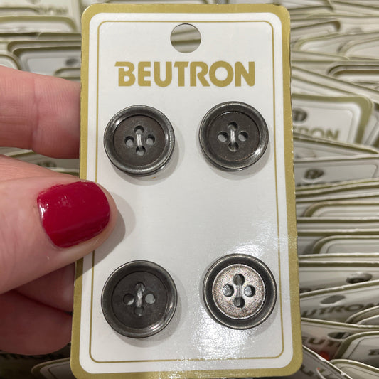 Card with four metal buttons held by a hand with red nail polish, with 'Beutron' branding.