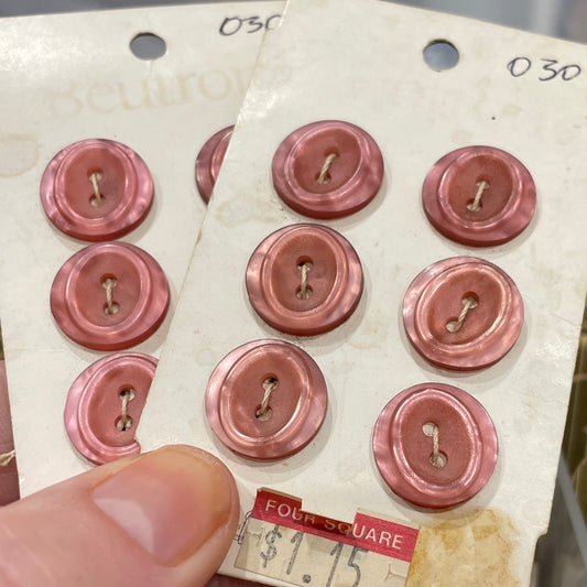 Card with pink buttons held by a hand in front of a blurred background