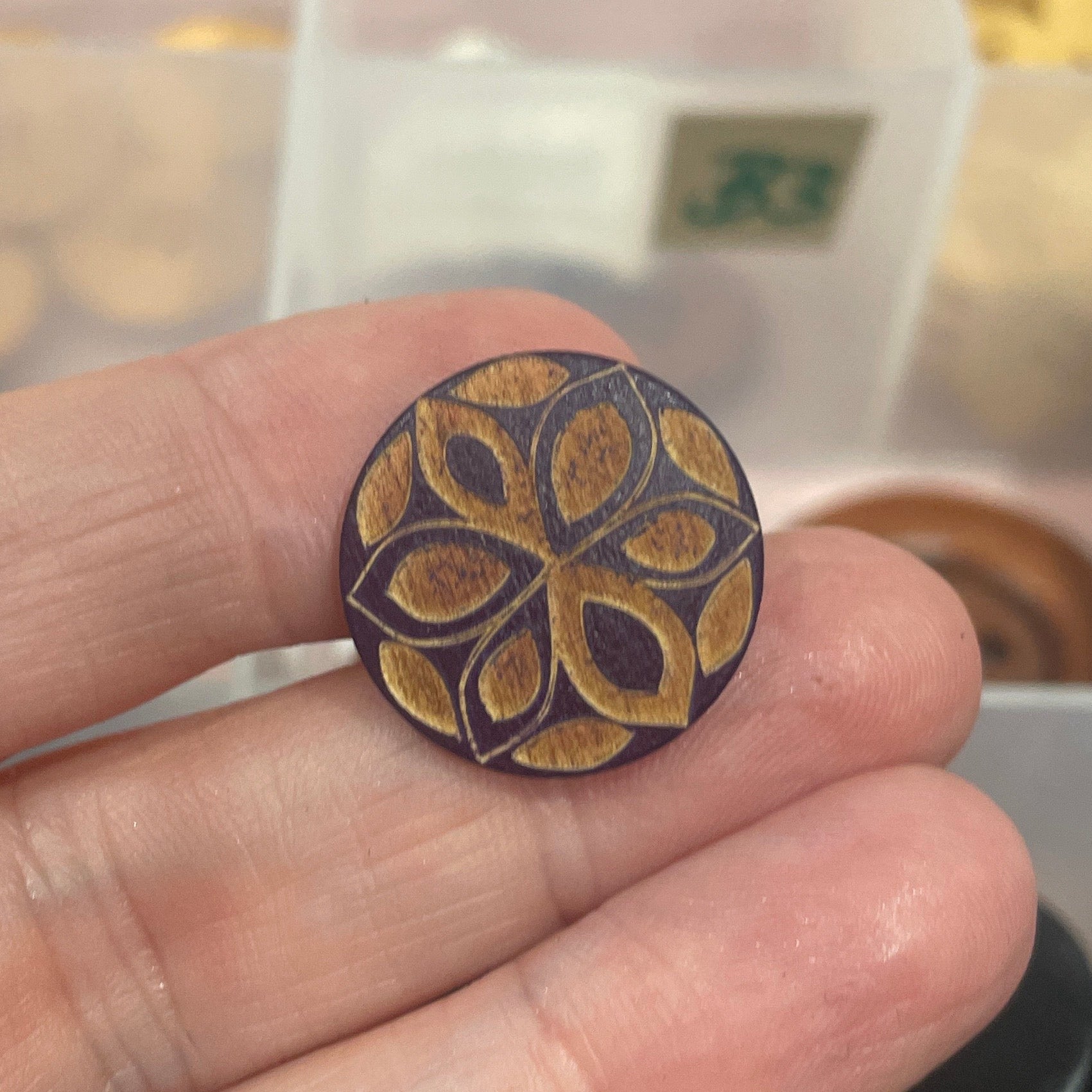 Hand holding a decorative wooden stamp with intricate designs, blurred background