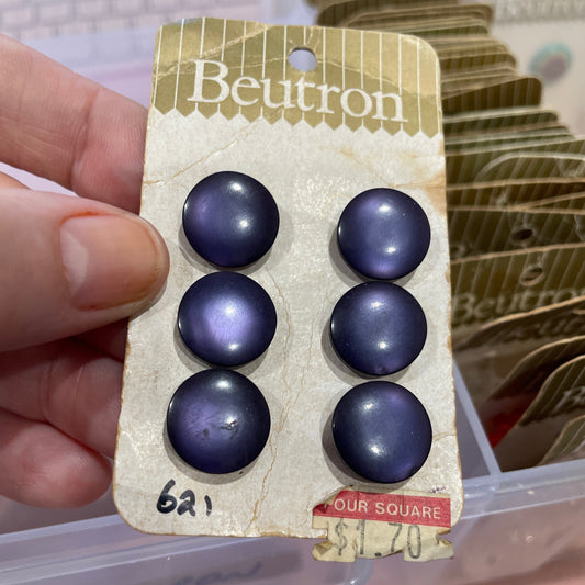 Purple buttons on a Beuton card held by a hand with a blurred background