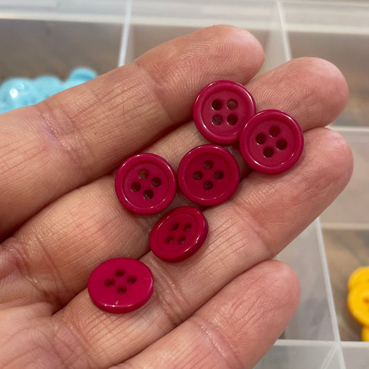 Hand holding red buttons with a background of colorful buttons in a container